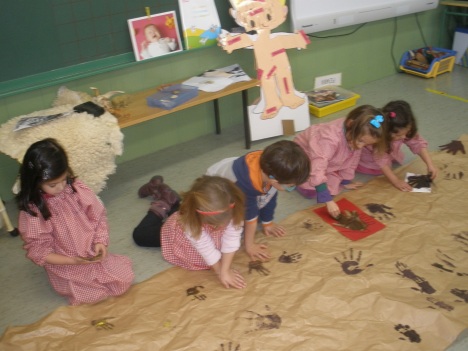 niños estampando manos para la decoración de la cueva